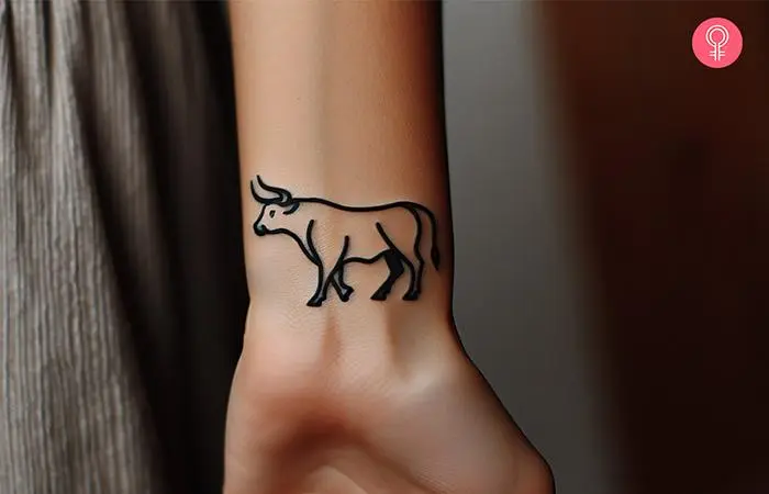 A woman with a bull outline tattoo on the wrist