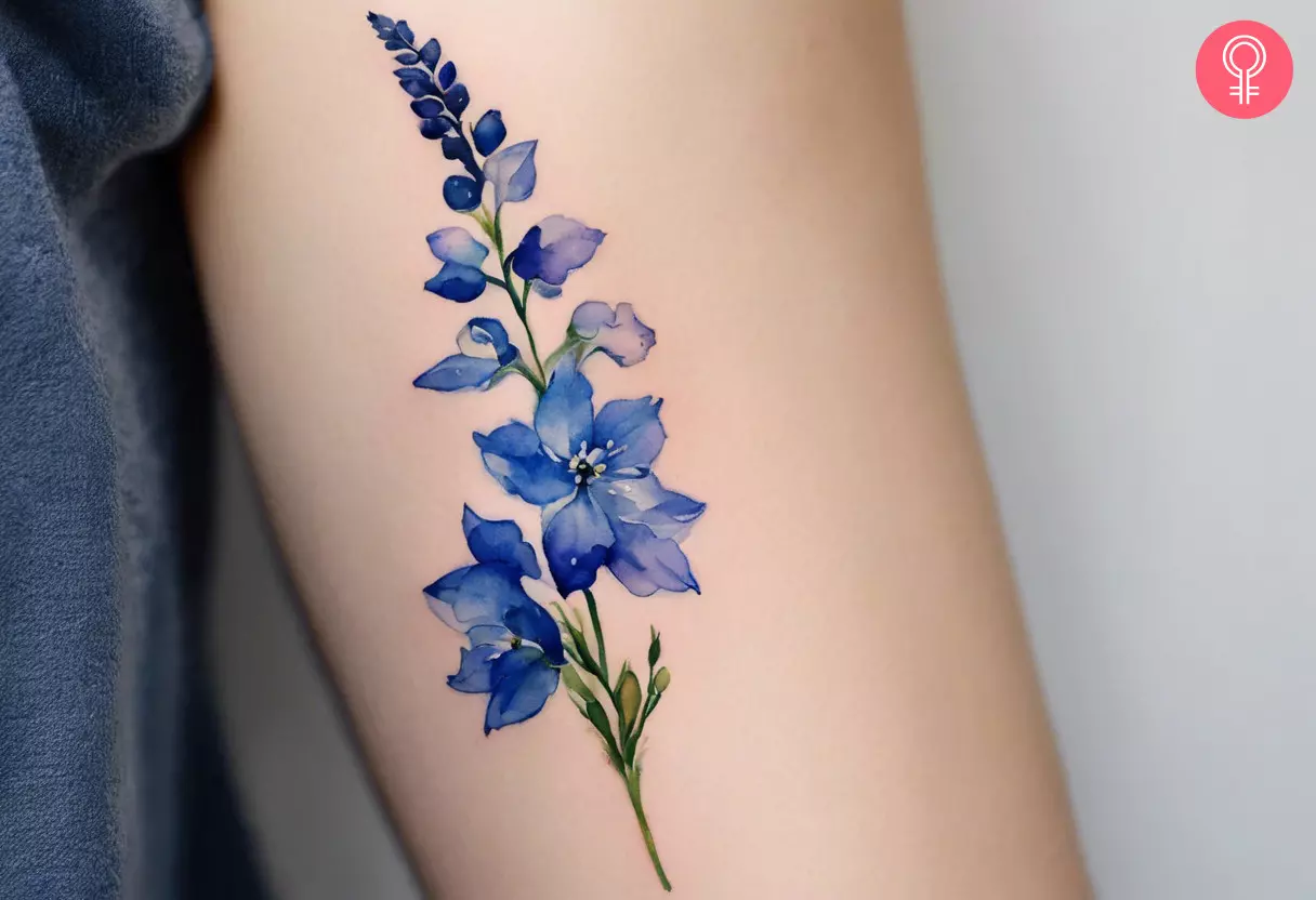 Woman with a delphinium birth flower tattoo on the upper arm