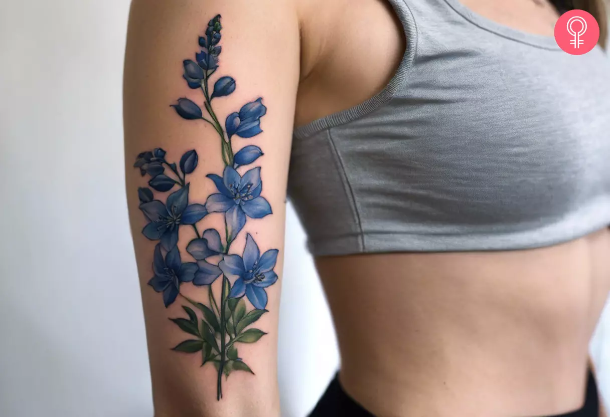 Woman with a delphinium cancer tattoo on the upper arm