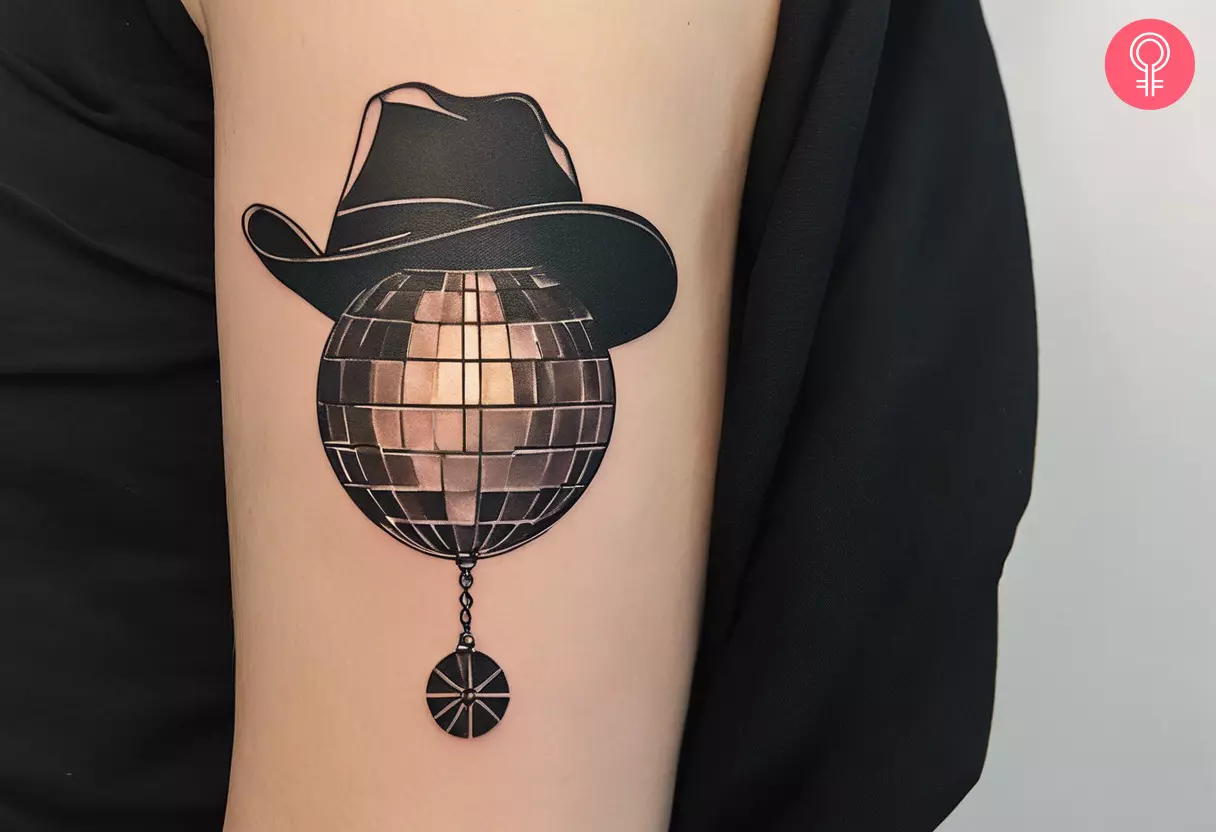 Disco ball cowboy hat tattoo on the upper arm