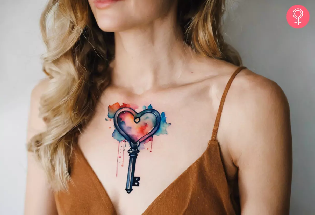A tattoo of a watercolor key with a heart design on a woman’s chest 