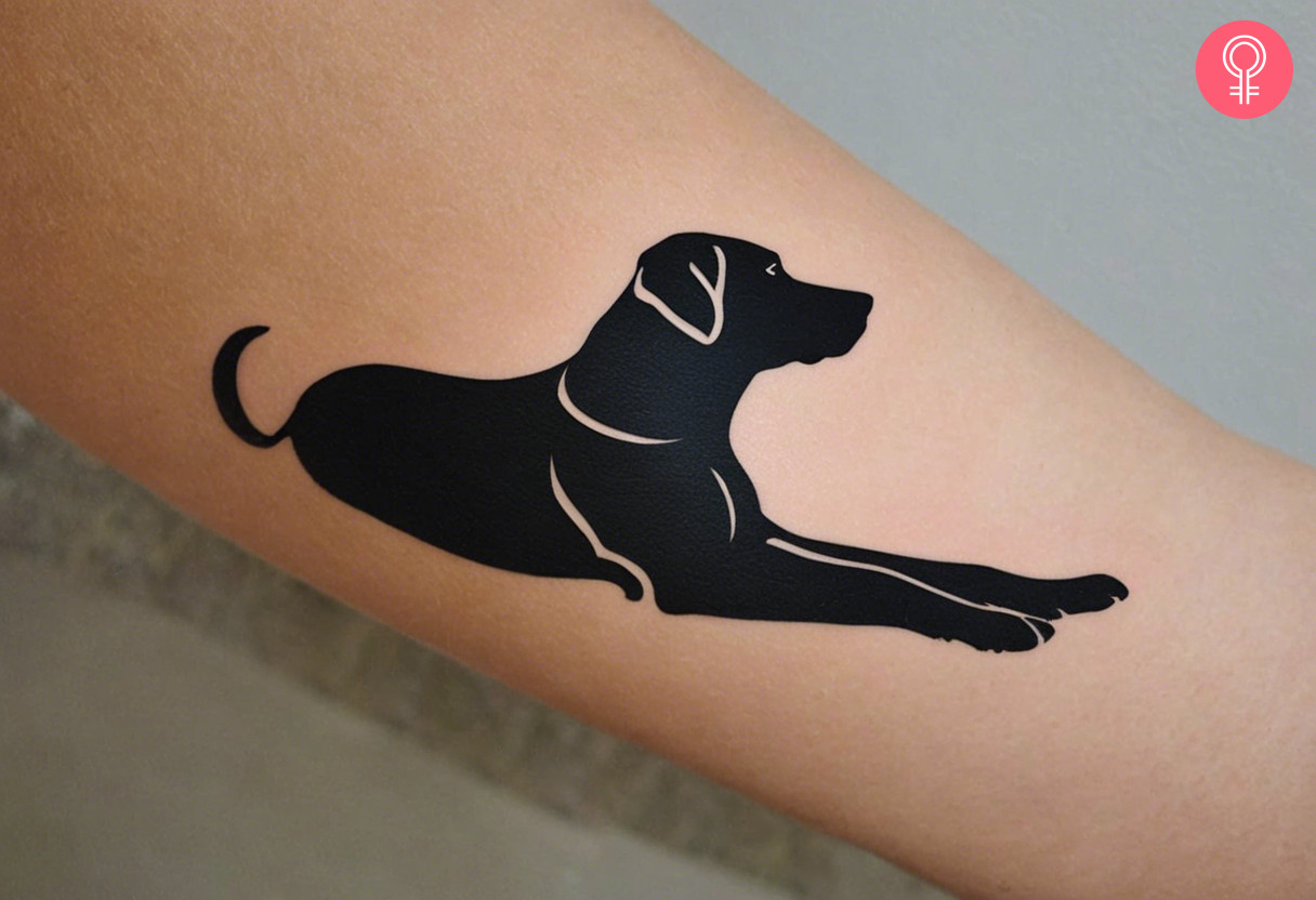 A Labrador silhouette tattoo on a woman’s forearm