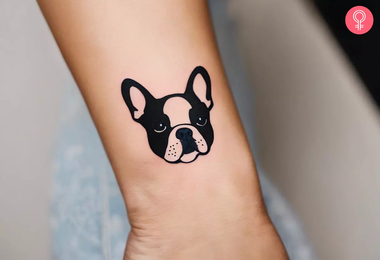 A minimalist French Bulldog face tattoo near the wrist