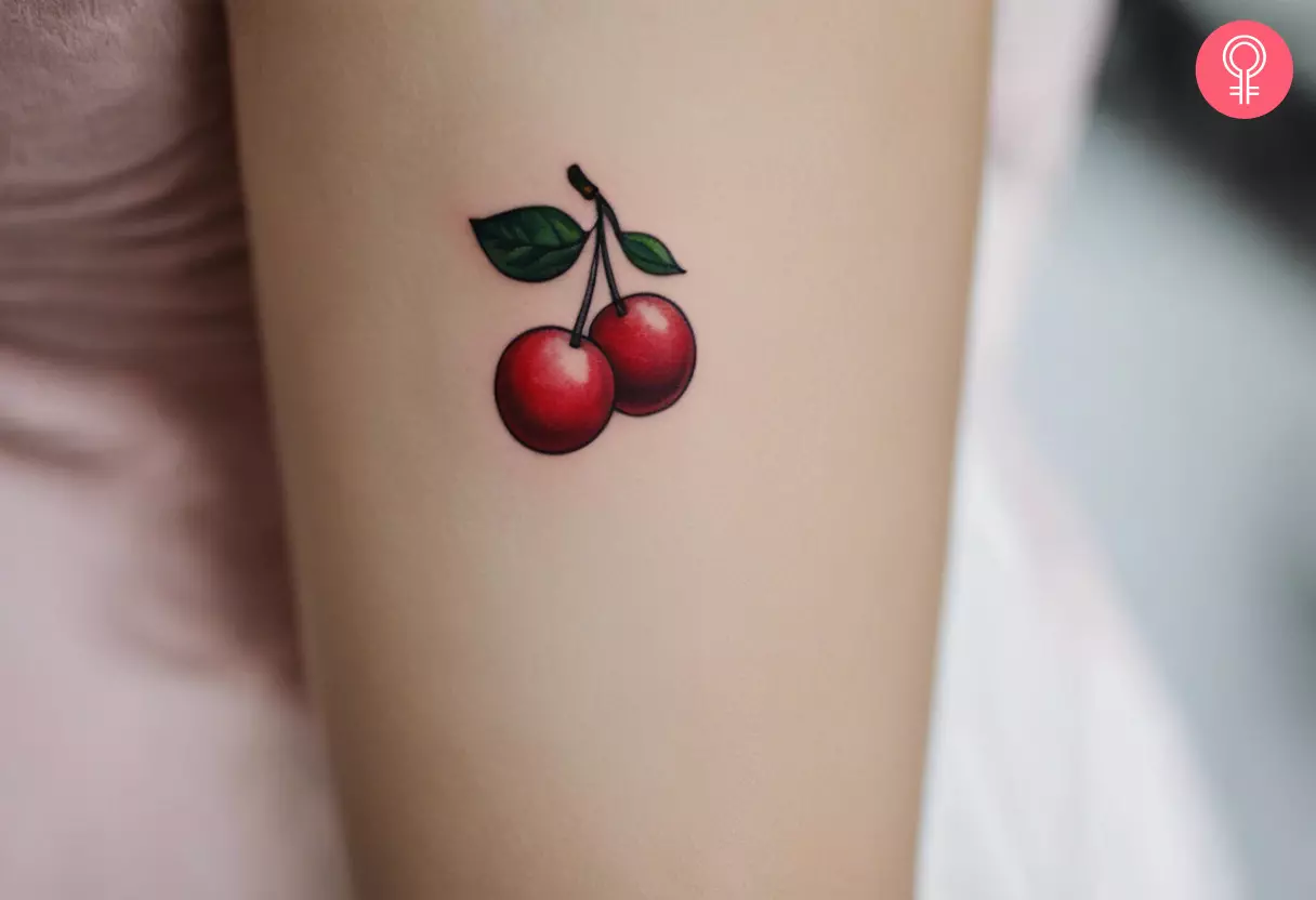 Minimalist cherry tattoo on the upper arm