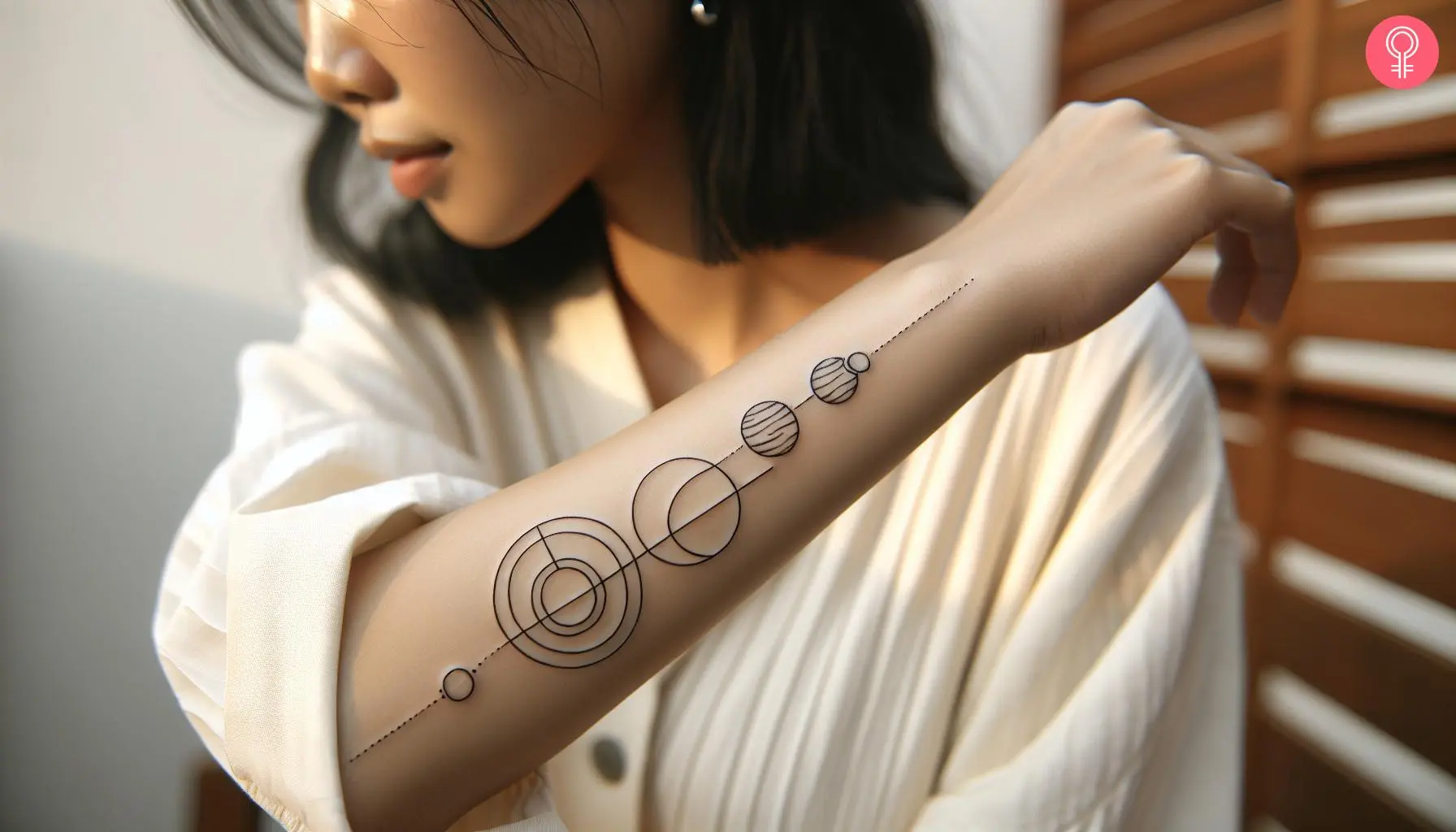 A woman with a minimalist geometric solar system tattoo design on her forearm