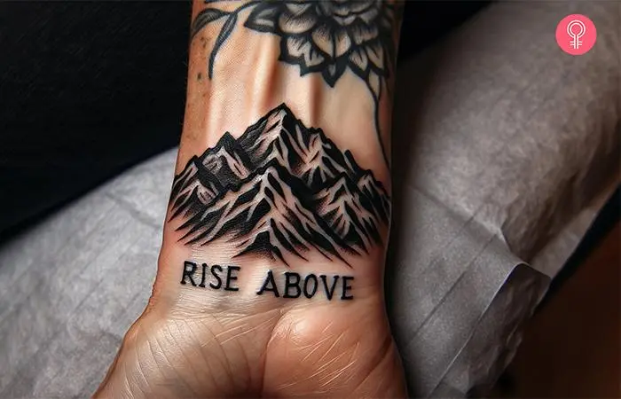 A man with a mountain tattoo with words on his wrist