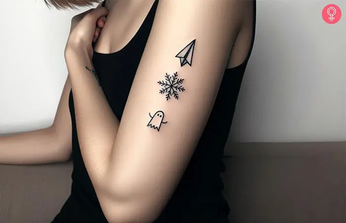 A paper airplane-snowflake-ghost tattoo on a woman’s arm