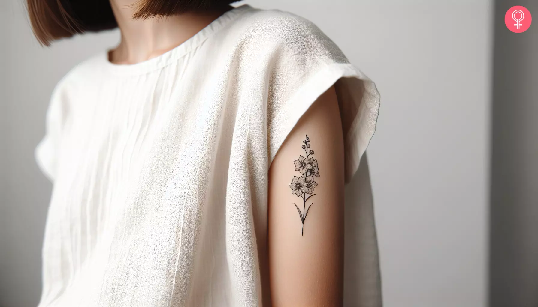 Woman with a small delphinium tattoo on the upper arm