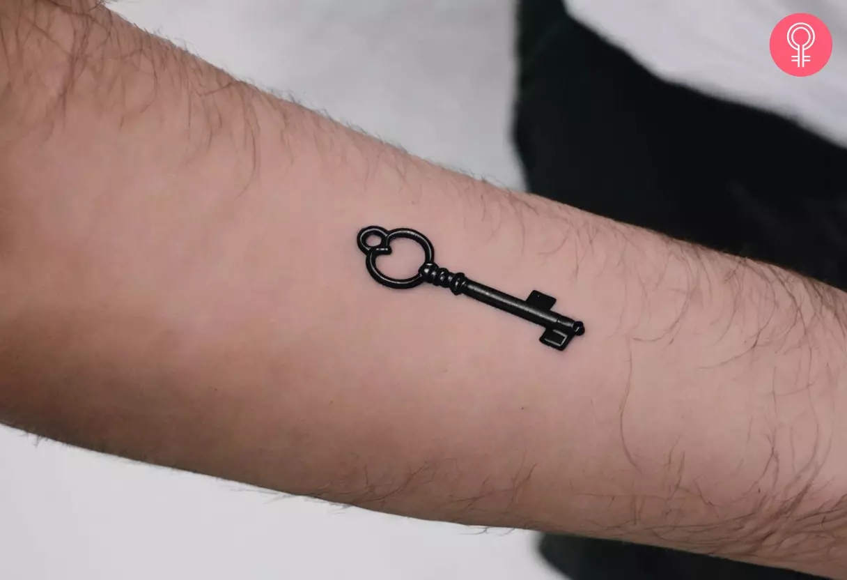Tattoo of a small key on a man’s forearm