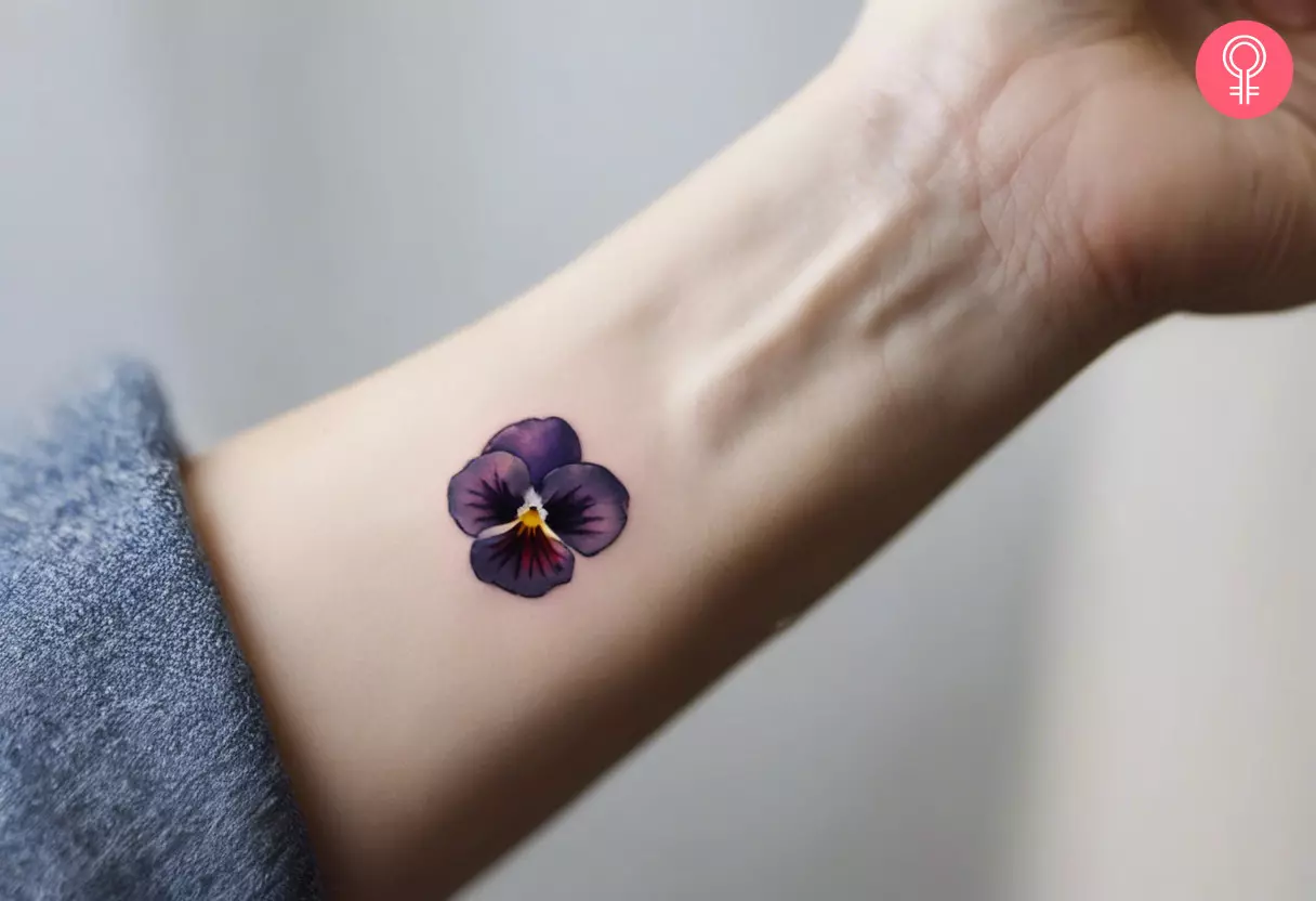 A small violet Pansy tattoo near the wrist