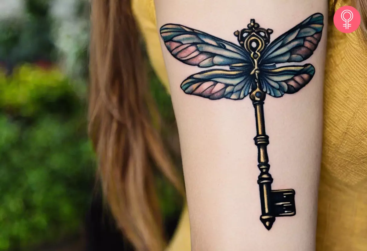 A woman with a dragonfly wings vintage key tattoo on her arm 