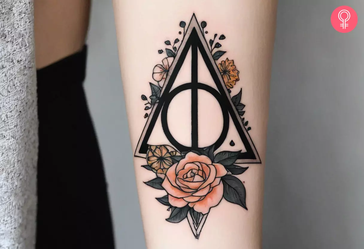 A woman with a feminine Deathly Hallows tattoo on her forearm