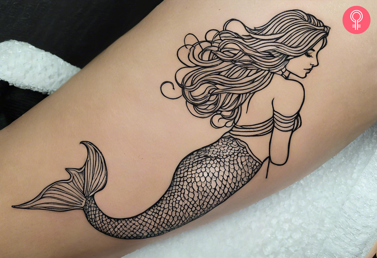 Woman with outline mermaid tattoo on her arm