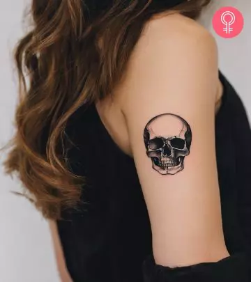 A woman sporting a skull and death grayscale tattoo on her upper back