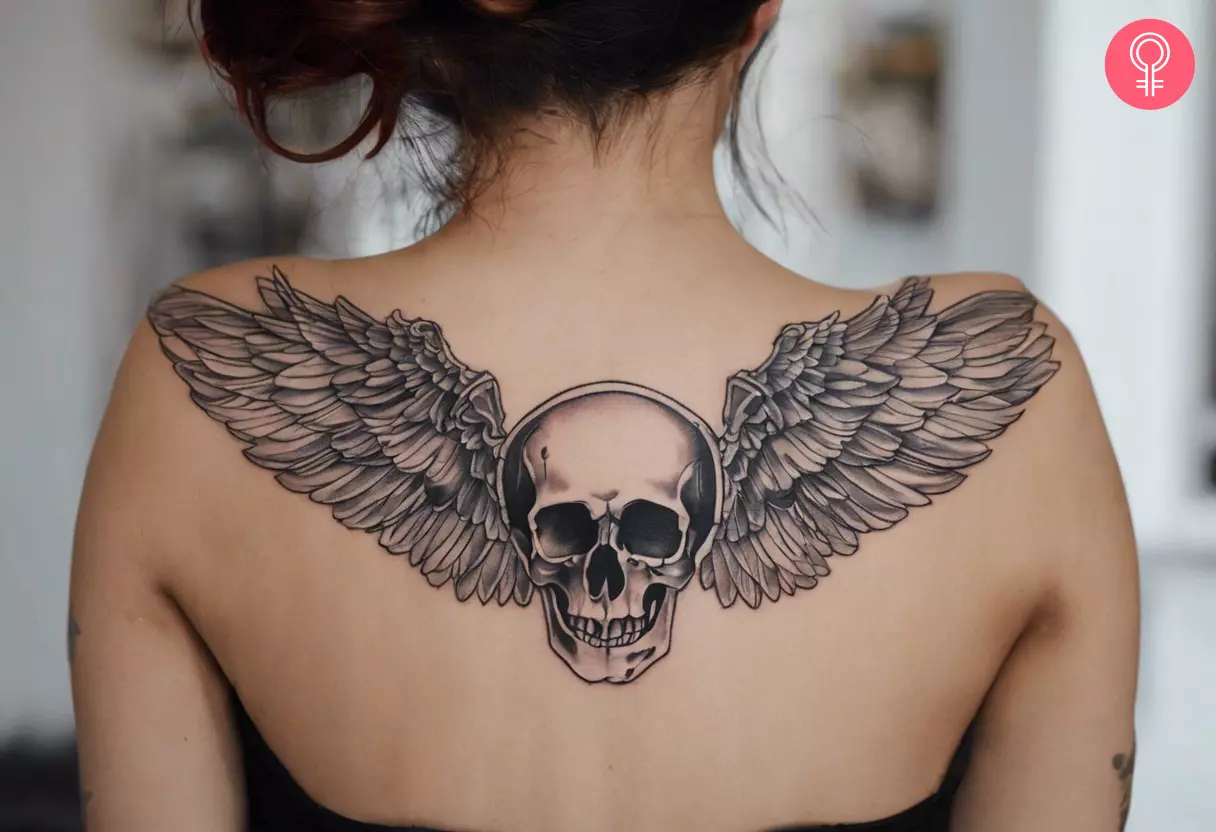 Woman with skull wings tattoo on her upper back