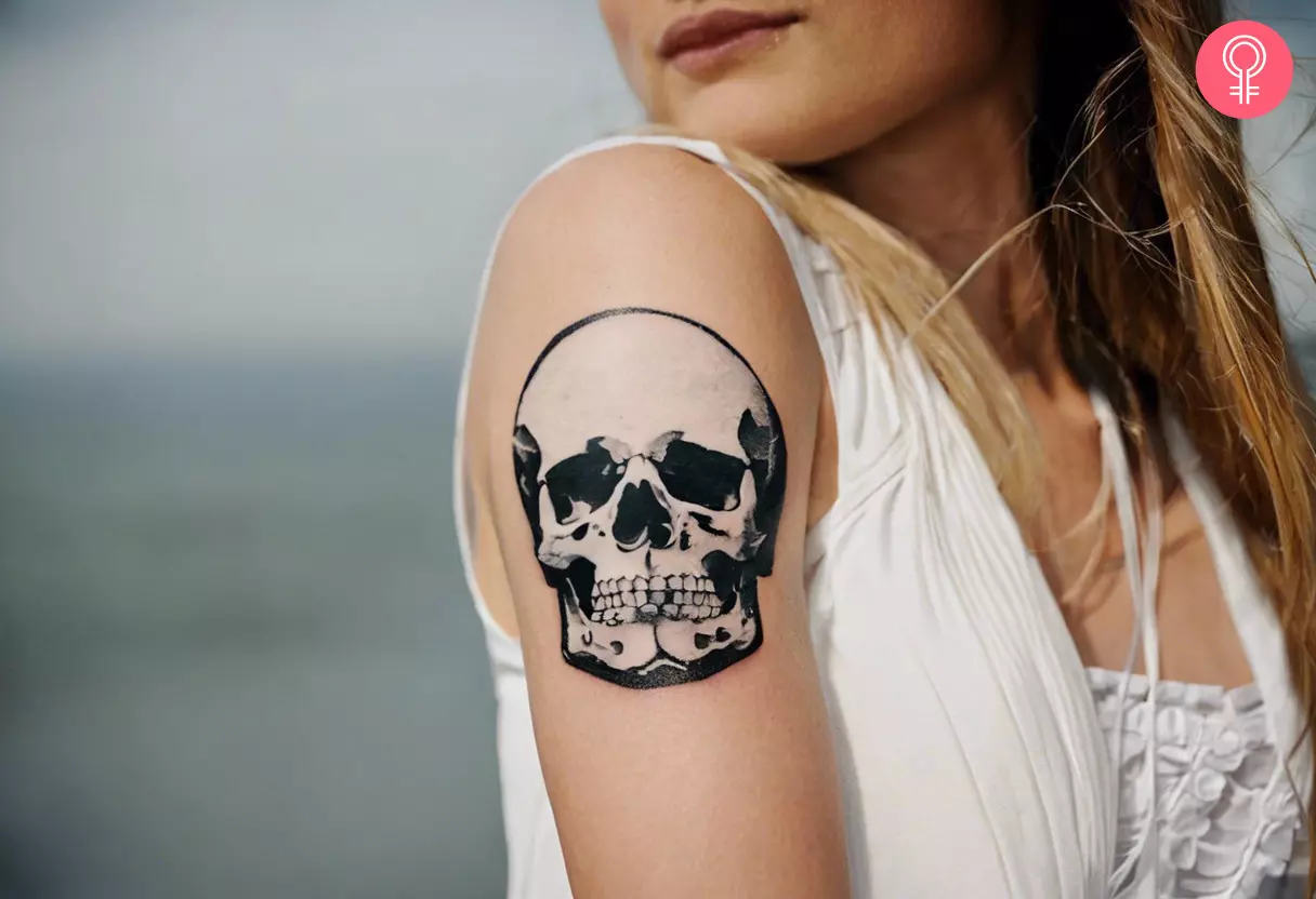 Woman with white ink skull tattoo on her outer arm