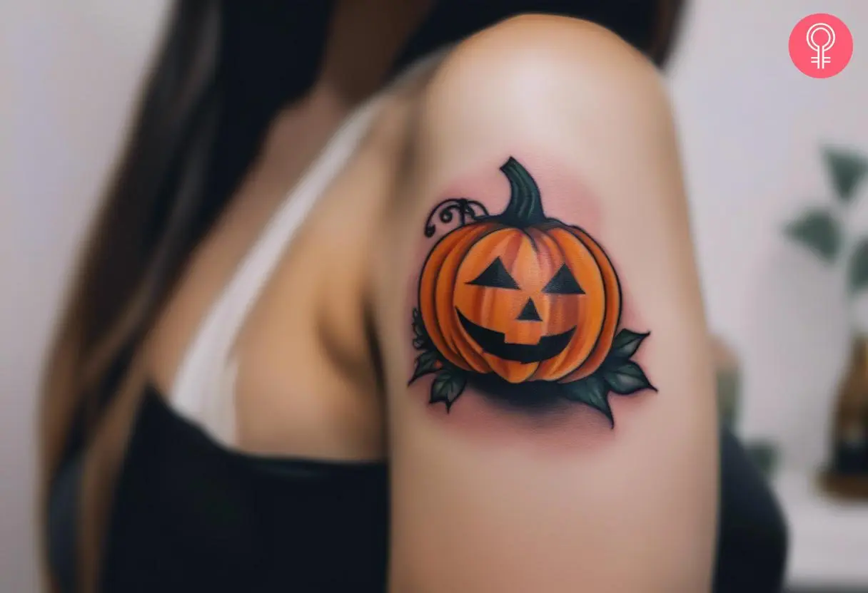 A Halloween pumpkin tattoo on the shoulder of a woman