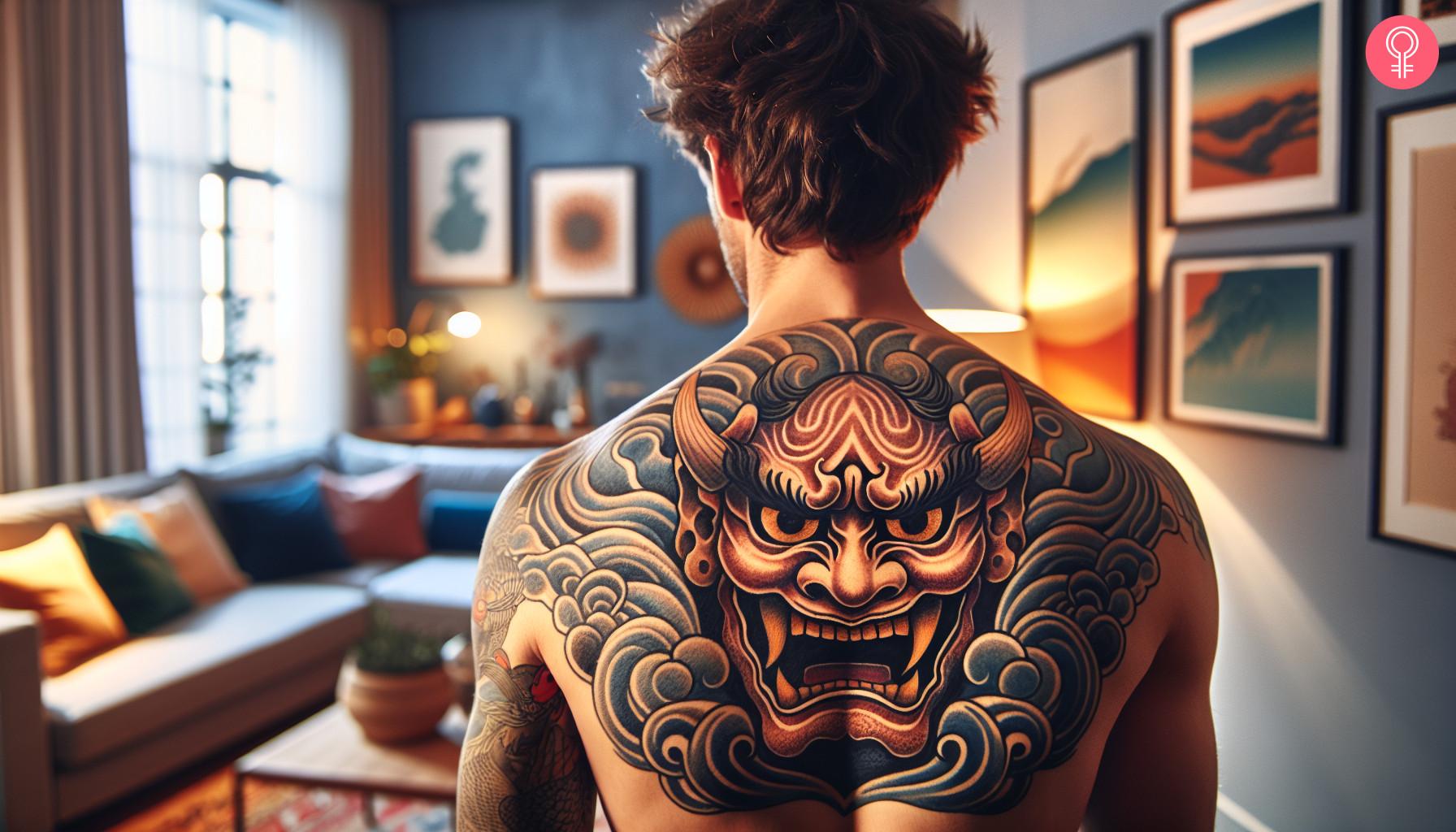 A Japanese demon mask tattoo on a man's upper back