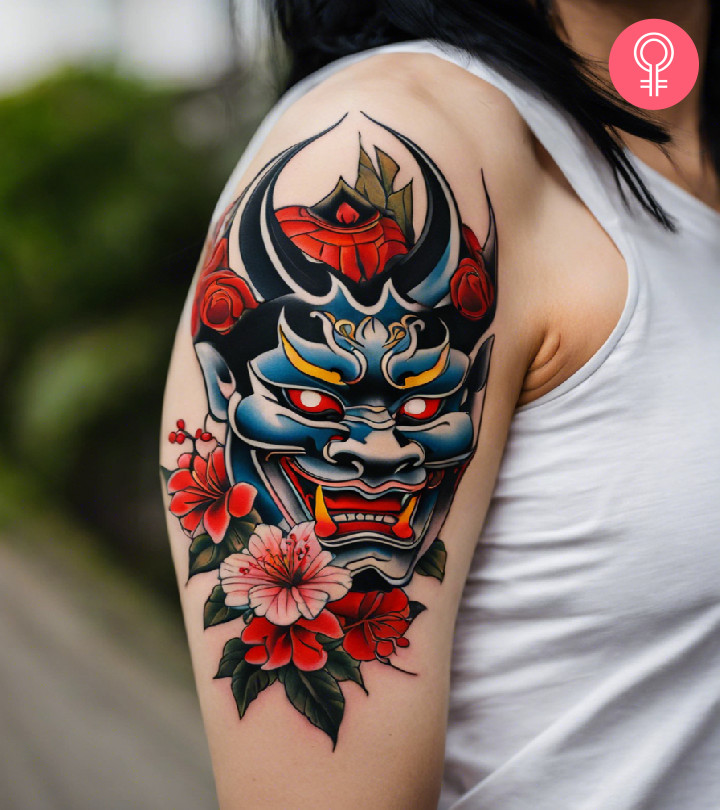 A Japanese mask tattoo on a woman’s upper arm