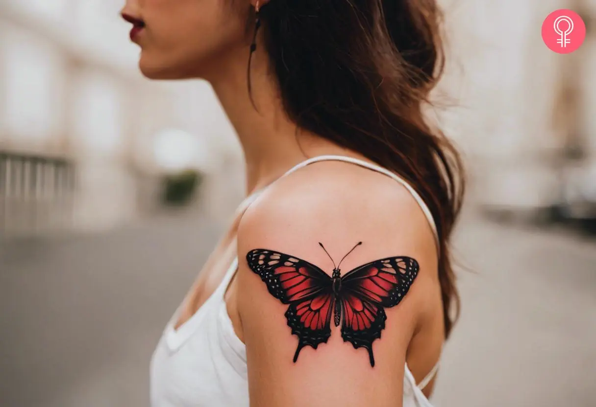 A black and red butterfly tattoo on a woman’s upper arm