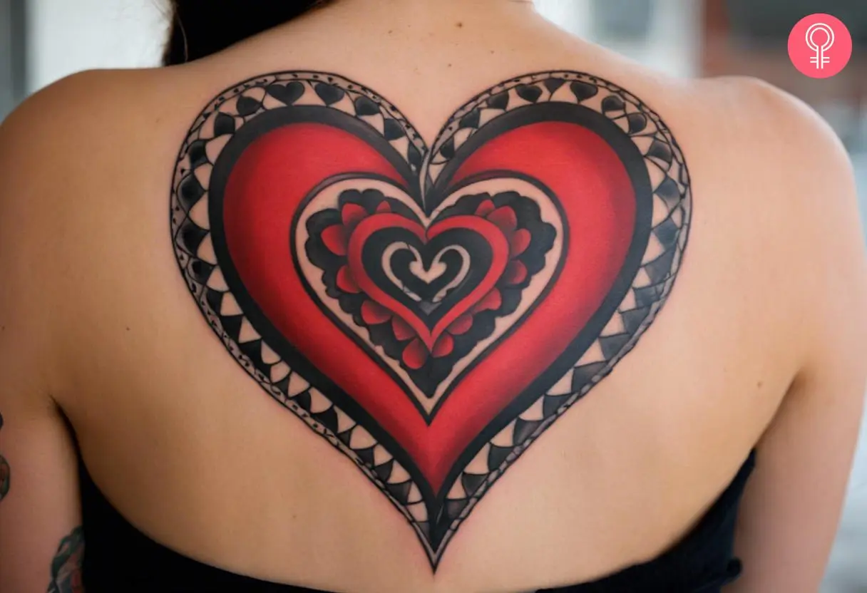 A black and red heart tattoo on a woman’s back