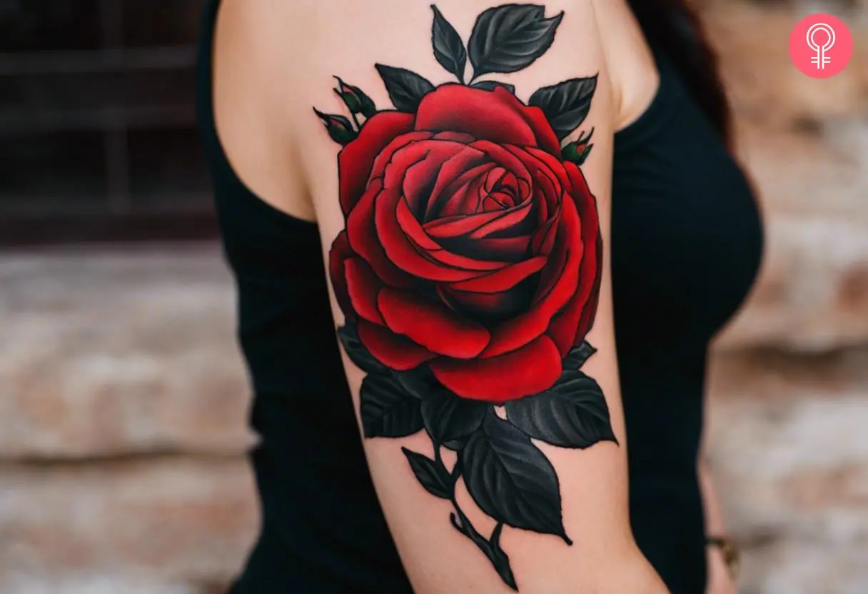 A black and red rose tattoo on the upper arm of a woman