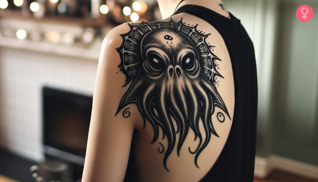 A black and white Cthulhu tattoo on a woman's shoulder