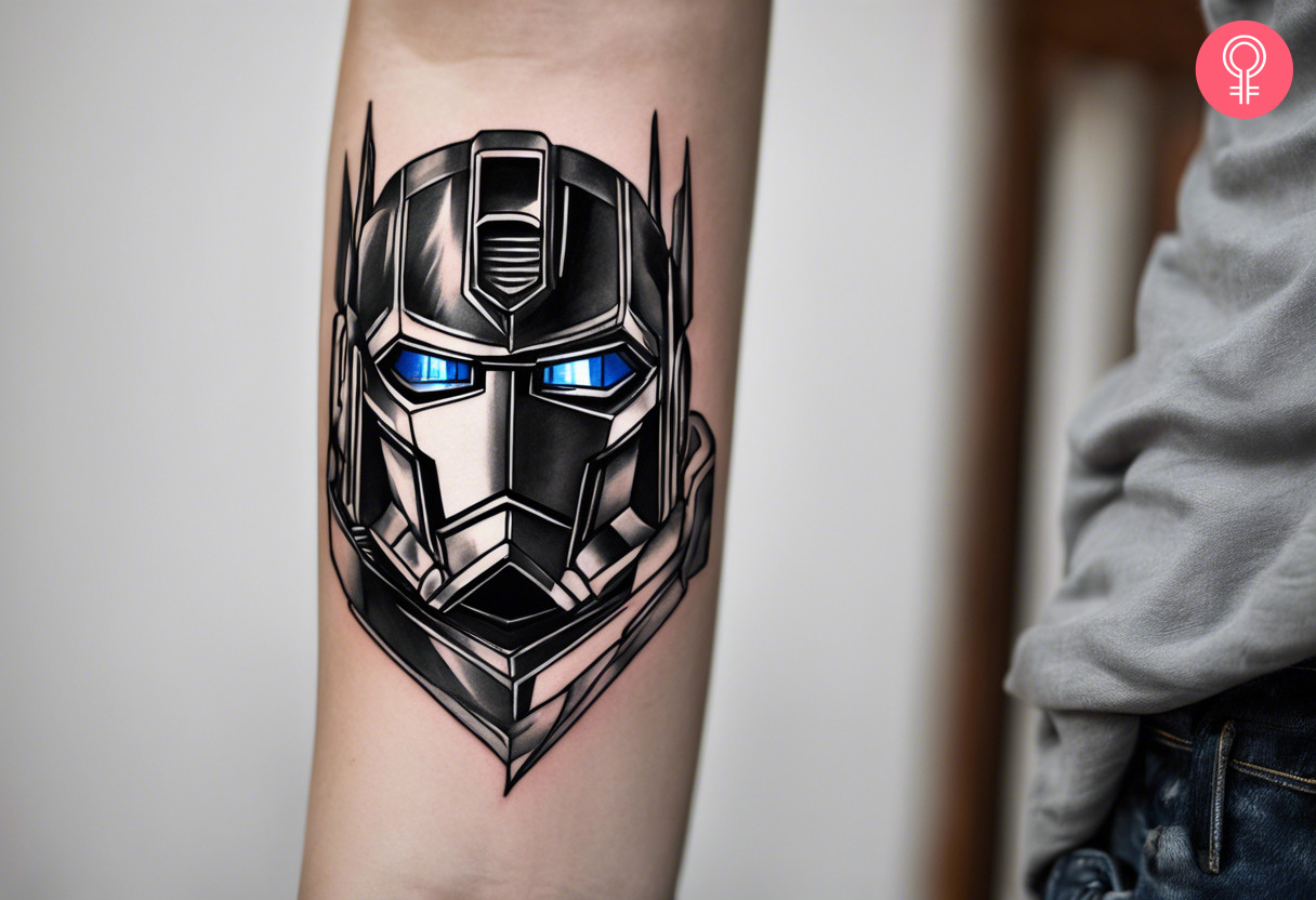 A black and white optimus prime tattoo with blue eyes on the forearm