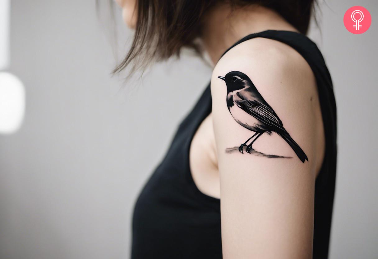 A black and white robin tattoo on the upper arm