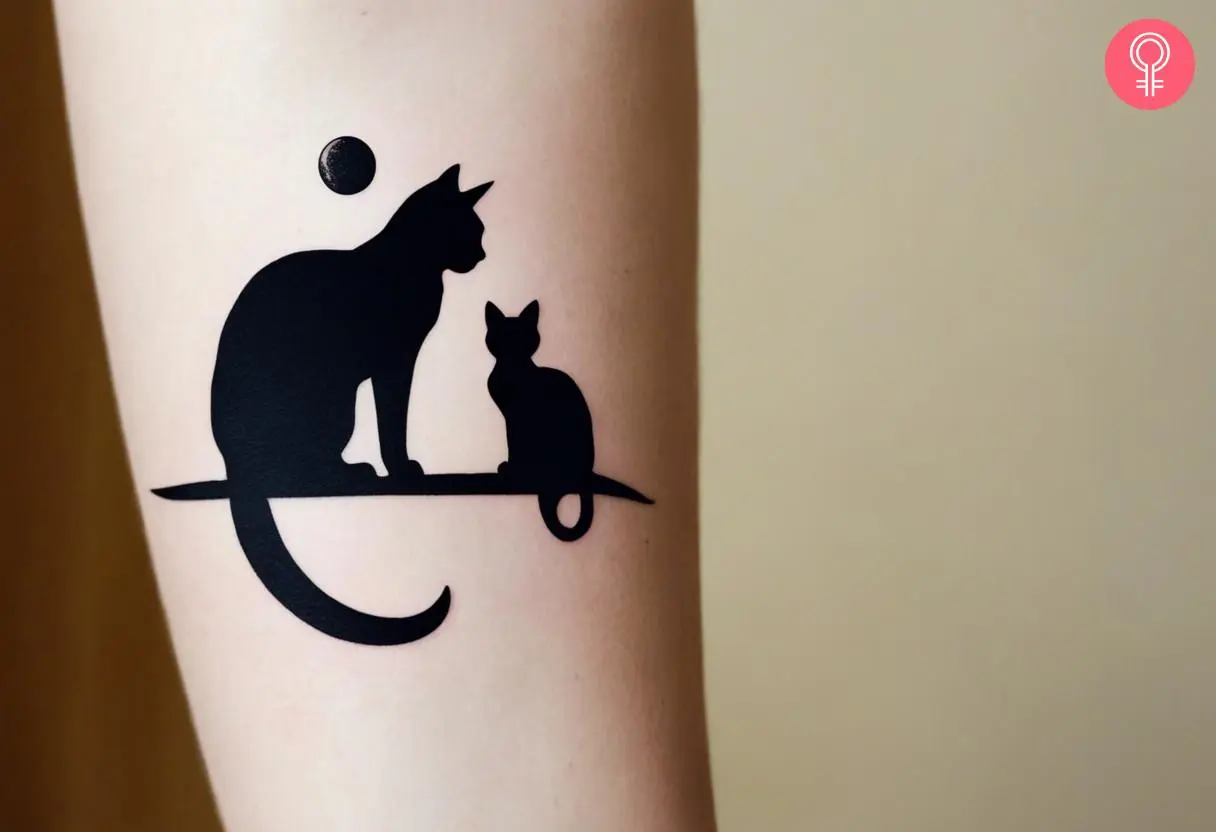 A cat and moon silhouette tattoo on the forearm