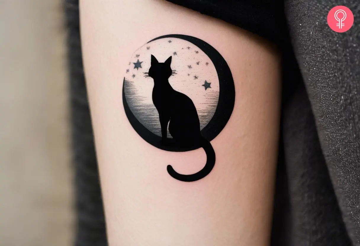 A cat moon and stars tattoo on the upper arm