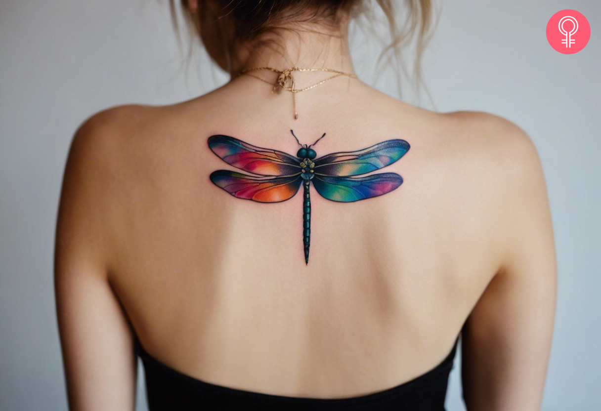 A colorful dragonfly on the upper back of a woman