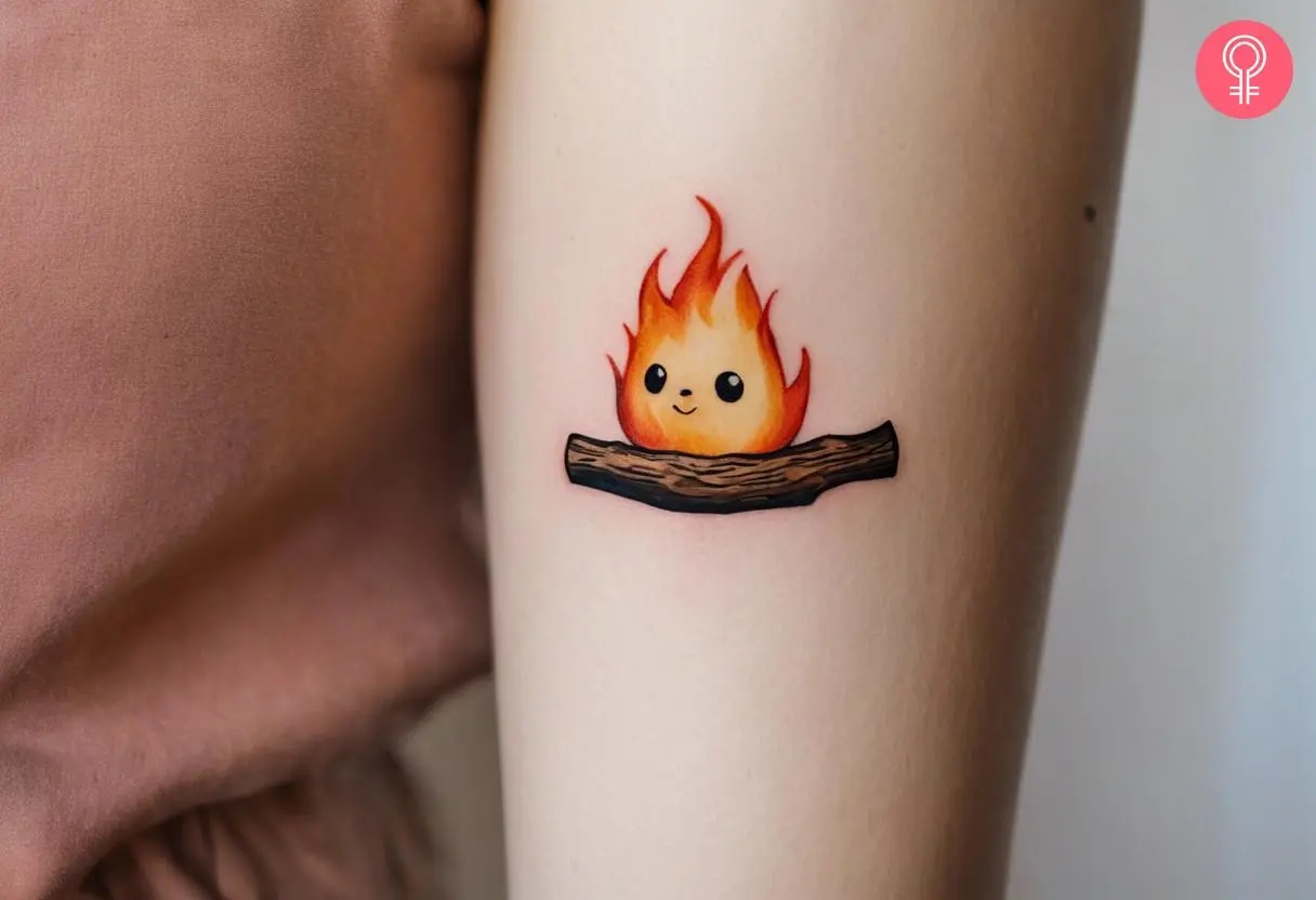 A cute Calcifer on a log tattoo on the upper arm