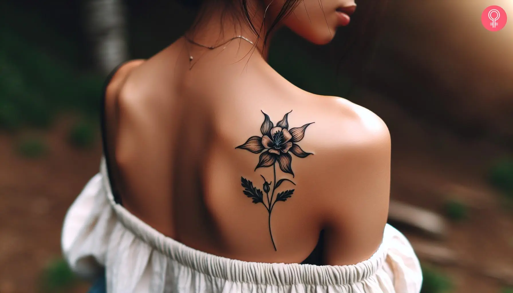 A delicate columbine flower tattoo on the back of the shoulder