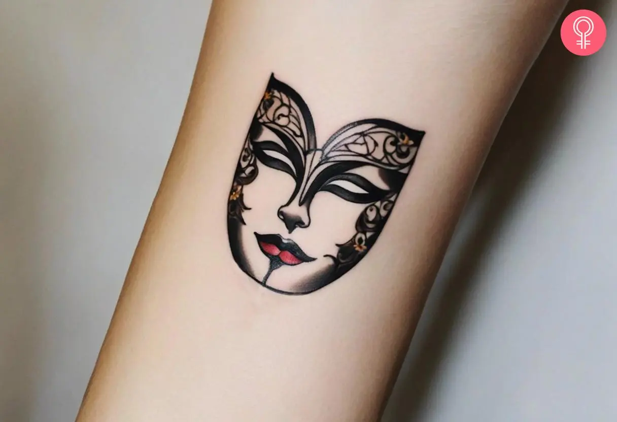 A female drama mask tattoo on the forearm