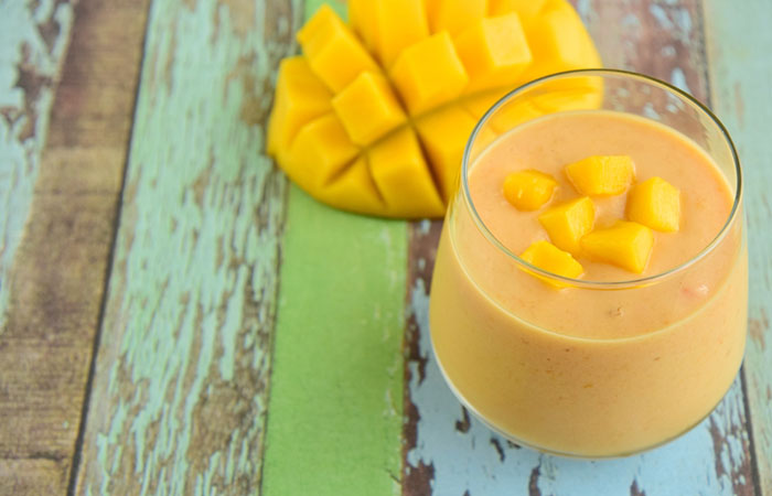 A glass of homemade Alphonso mango and almond milk protein shake on the table