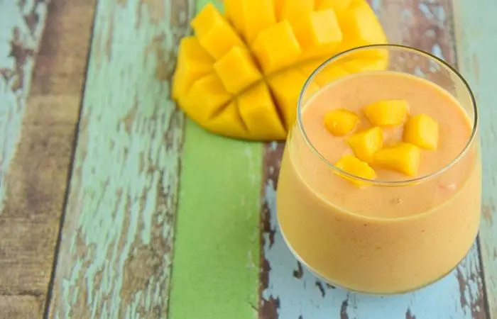 A glass of homemade Alphonso mango and almond milk protein shake on the table