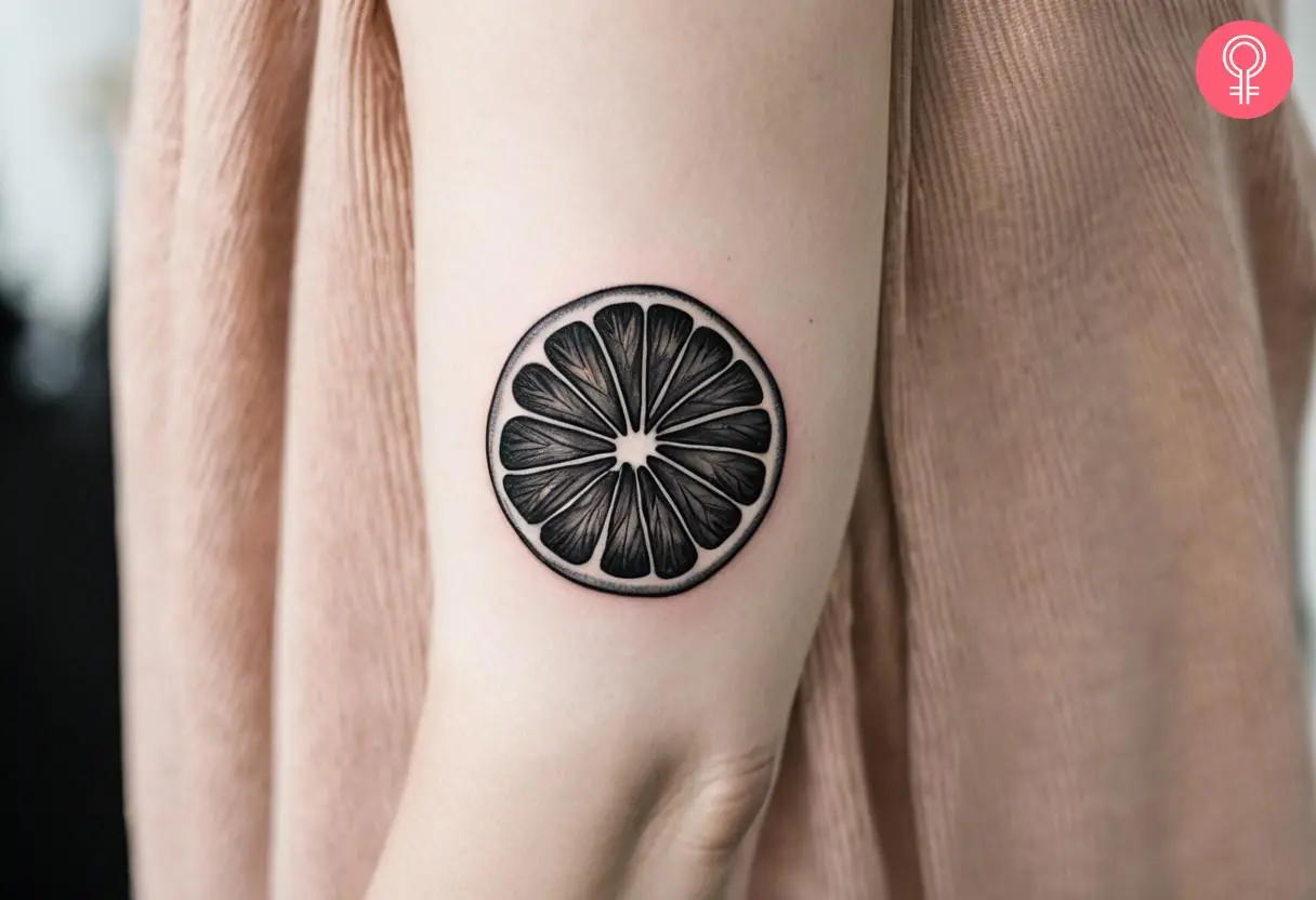 A lime tattoo in black and white on a woman’s upper arm