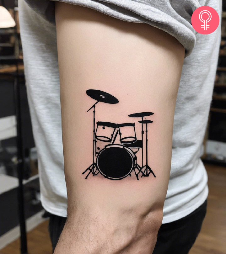 A man wearing a minimalistic drum tattoo on the upper arm.