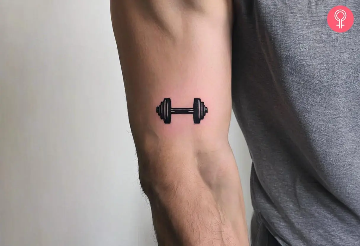 A man with a small dumbbell tattoo on his upper arm