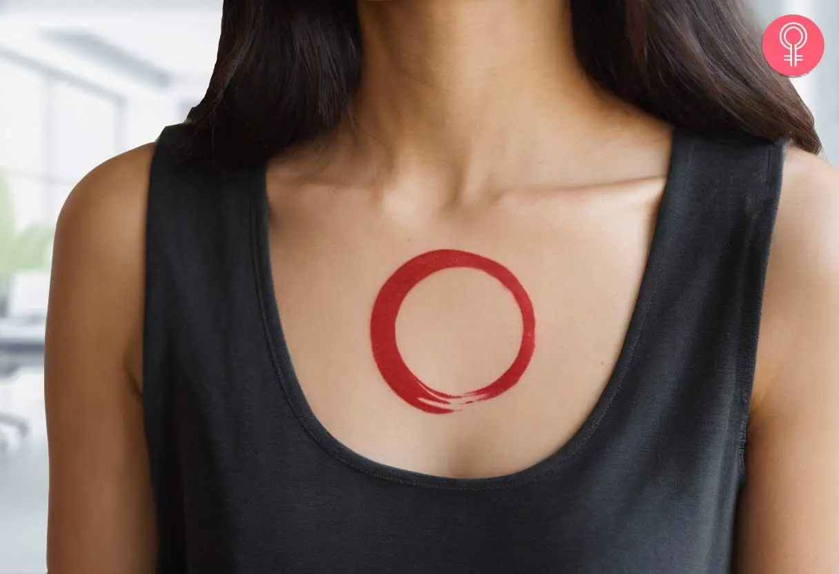 A minimalist enso tattoo on a woman’s chest