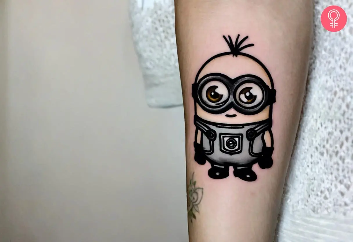 A minion tattoo black and white on forearm of a woman