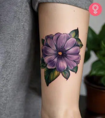 A woman wearing a violet flower tattoo on her upper arm