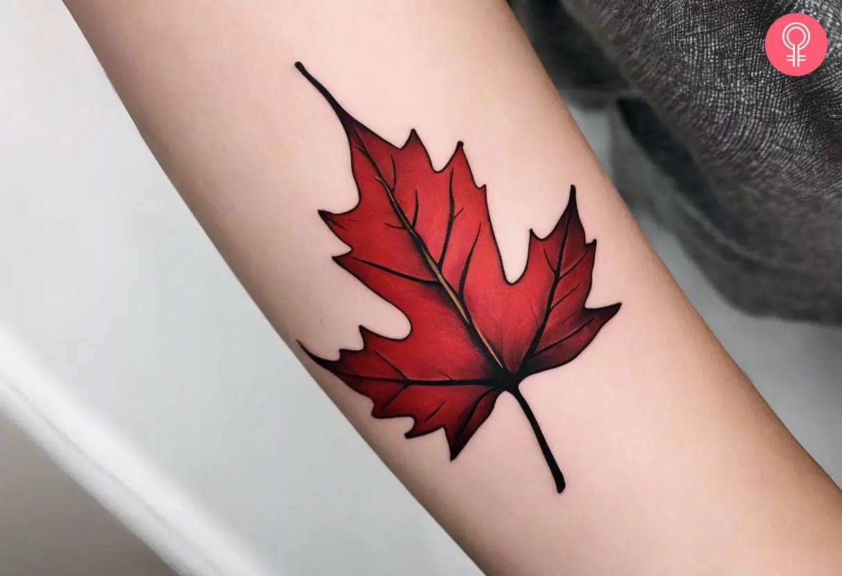 A red maple leaf tattoo on a woman’s forearm