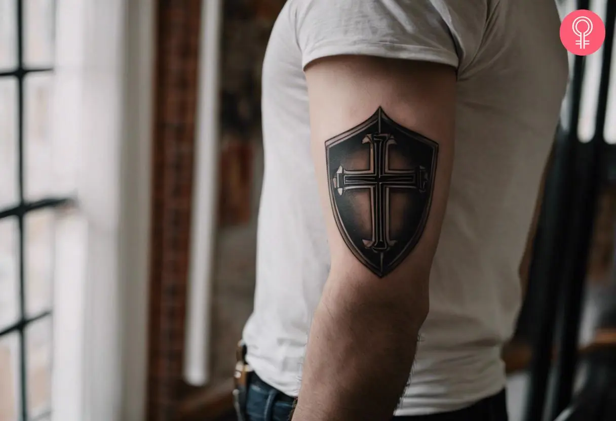 A simple shield tattoo with a Cross in the middle