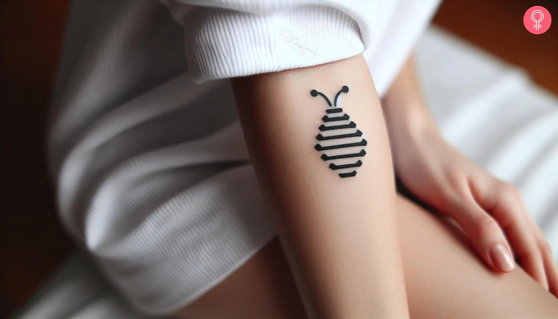 A small beehive tattoo on the forearm of a woman