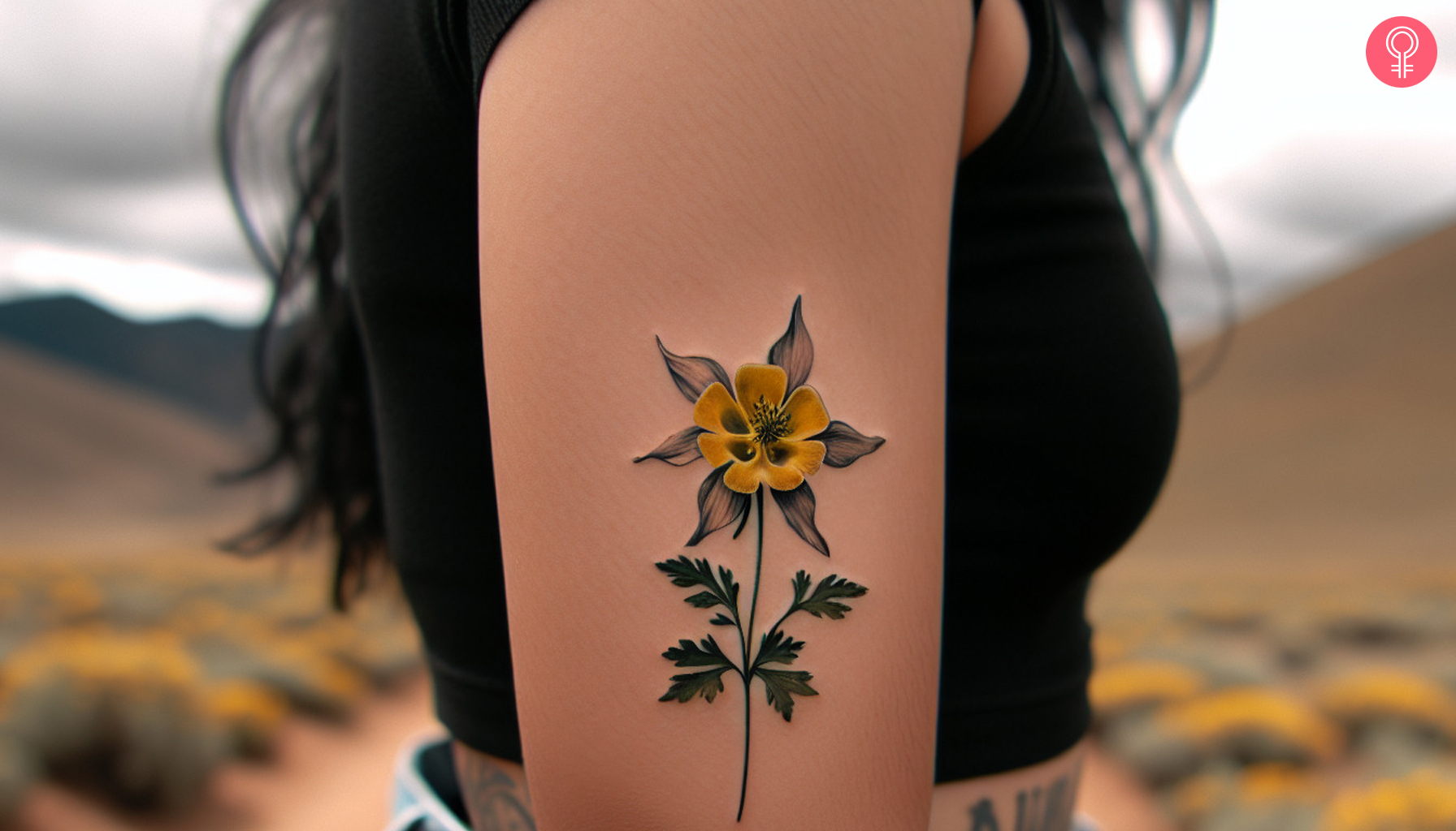 A small yellow and black columbine flower tattoo on the upper arm