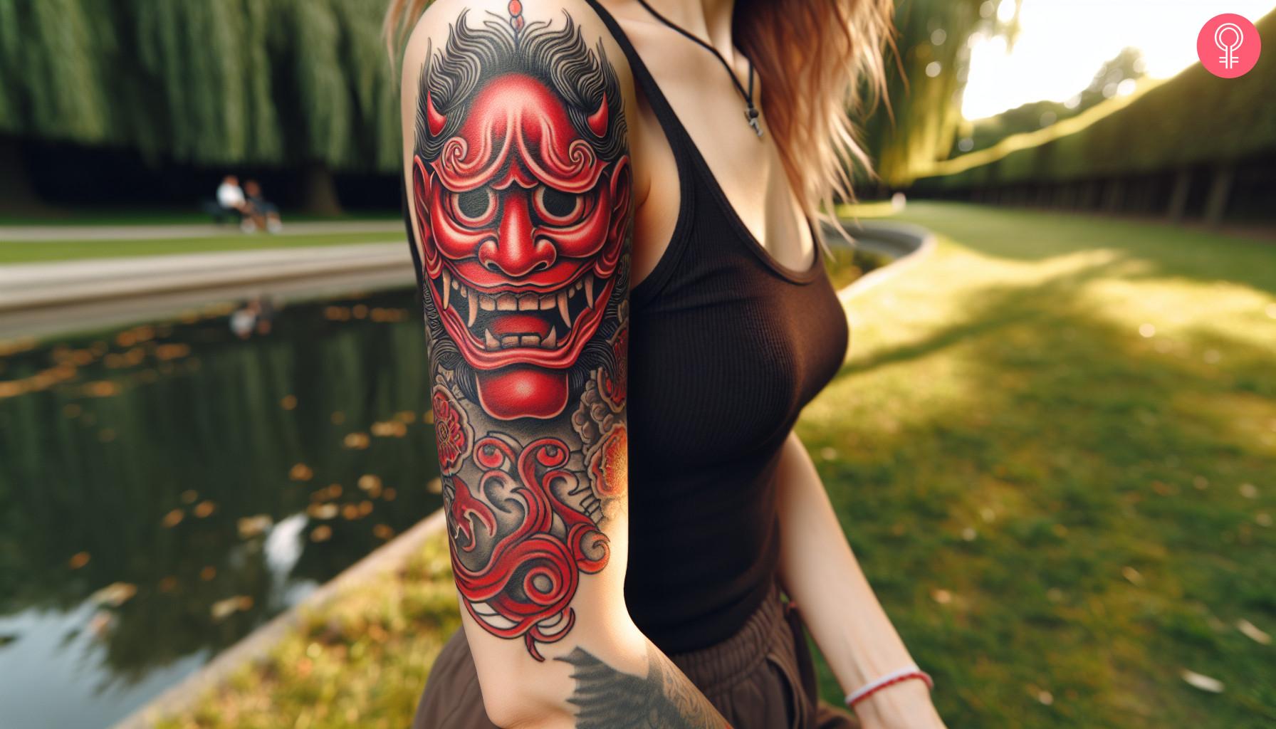 A traditional Japanese mask tattoo on a woman's upper arm