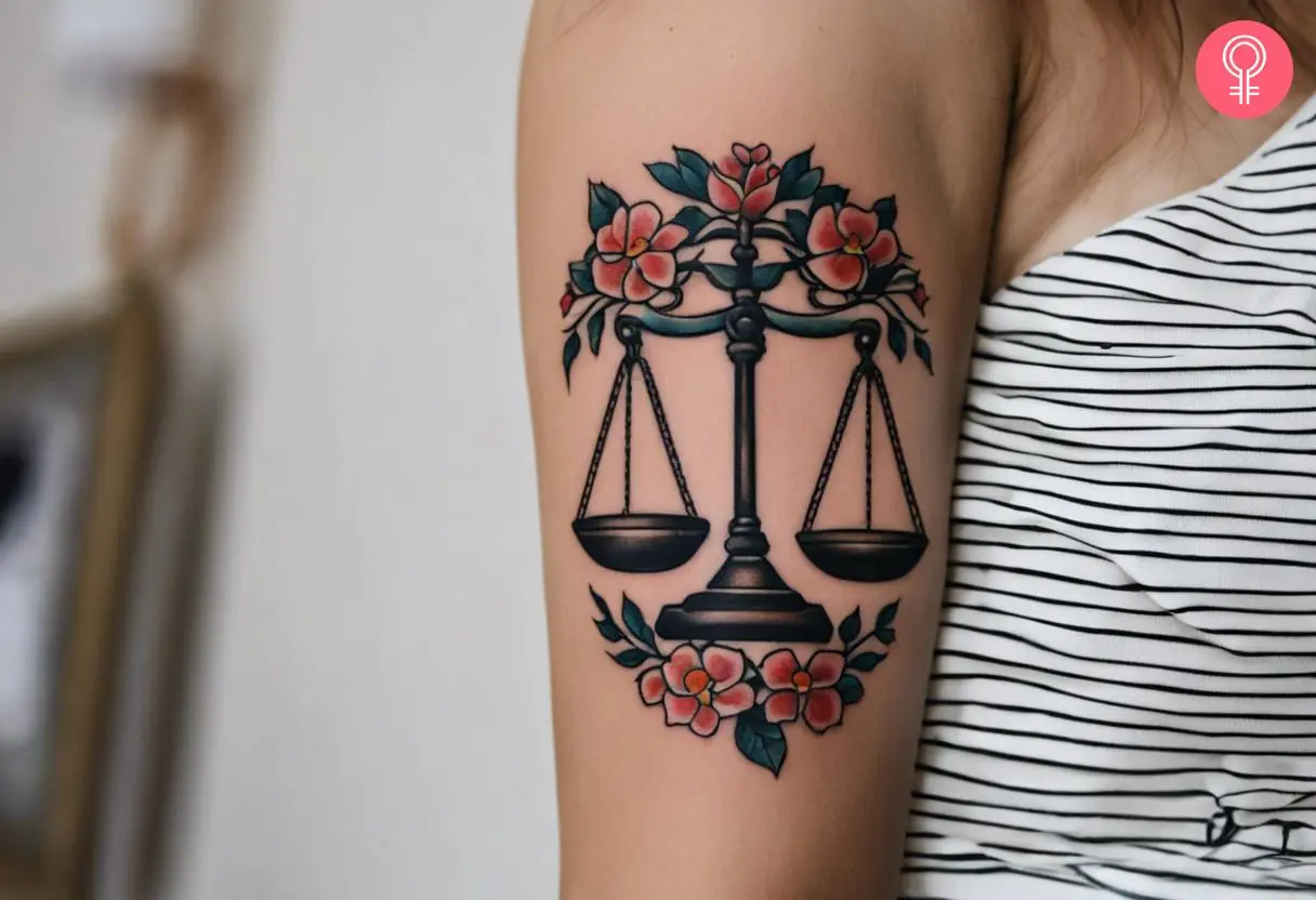 A traditional scales of justice tattoo on the upper arm of a woman