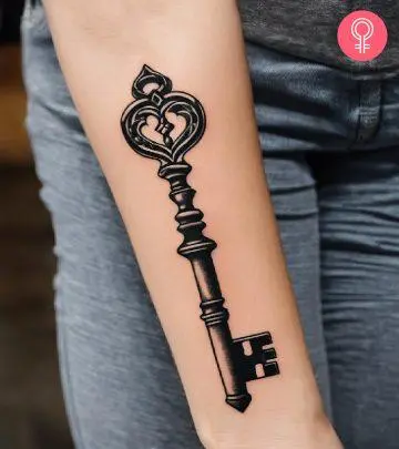 A vintage key tattoo on the forearm